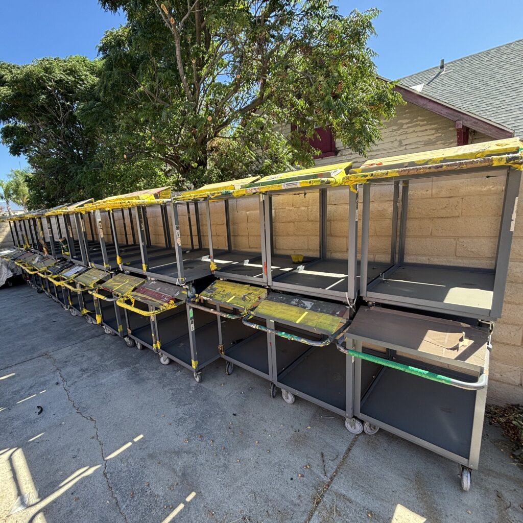 Row of steel utility carts with yellow rails, outdoors